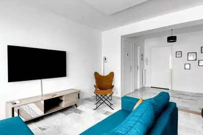 a living room with a blue couch and a flat screen tv at 4P Modern & Secured Parking in Le Cannet