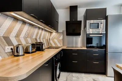 a kitchen with black cabinets and a wooden counter top at 4P Modern & Secured Parking in Le Cannet
