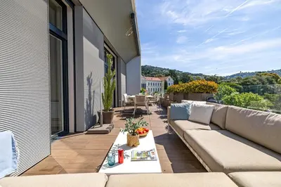 a patio with a couch and a table on a balcony at LE BOREAL penthouse avec terrasse et vue panoramique spectaculaire sur la ville in Cannes