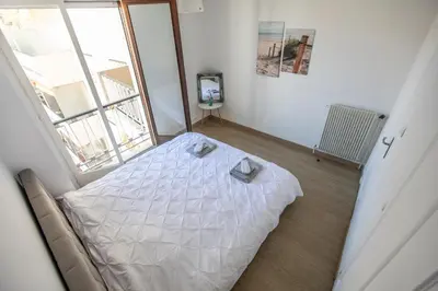 a white bed in a room with a large window at ++++ renovated cosy 50m2 sunny flat / balcony / close to beach and to the Palais des festivals ++++ in Cannes