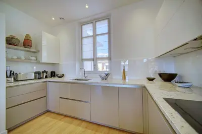 a white kitchen with white cabinets and a window at IMMOGROOM - Magnificent 180m duplex apartment - Parking - Air conditioning in Cannes