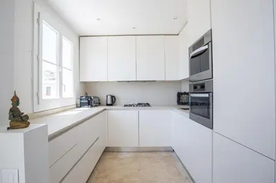 a white kitchen with white cabinets and a window at Art Deco Luxury Apartment with Breath Taking View on Cannes Bay by Olidesi in Cannes