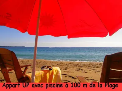 a beach with a red umbrella and chairs on the sand at Cannes Plage in Cannes