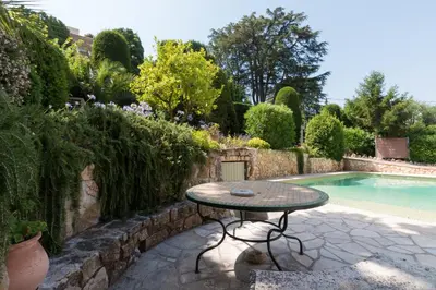 a table sitting next to a pool in a garden at Villa Tsavorite - Cannes Californie in Cannes