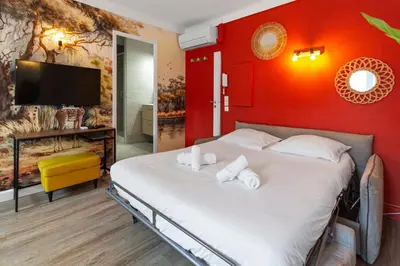 a bedroom with a bed with a red wall at Le Carnot - HYPERCENTRE - Cosy & Climatisation in Cannes