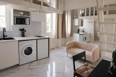 a white kitchen with a washing machine and a chair at Studio chic rénové à 5 min du Palais & de la Croisette Cannes in Cannes