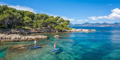 two people are standing on paddle boards in the water at Flo & Rose Azur - Duplex vue mer terrasses piscine jardins parking in Cannes