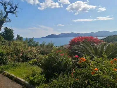 a garden with flowers and a view of the water at Flo & Rose Azur - Duplex vue mer terrasses piscine jardins parking in Cannes