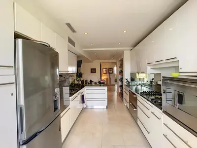 a large kitchen with white cabinets and a stainless steel refrigerator at FRGK 