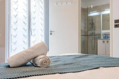 a rolled up towel on a bed with a shower at Palm Beach - swimming pool - beach at few steps in Cannes