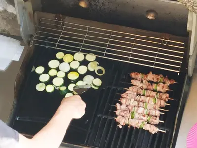 a person is cooking meat and vegetables on a grill at Rez-de-villa Mougins in Mougins