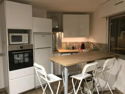 a kitchen with a wooden table and white appliances at Magnifique appartement pied dans l'eau in Cannes