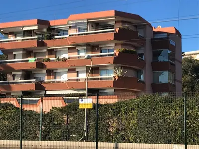 an apartment building with a fence in front of it at Magnifique appartement pied dans l'eau in Cannes