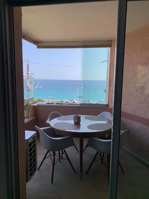 a table and chairs in a room with a view of the ocean at Magnifique appartement pied dans l'eau in Cannes