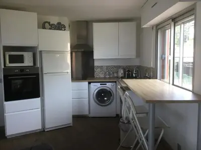 a kitchen with a white refrigerator and a washing machine at Magnifique appartement pied dans l'eau in Cannes