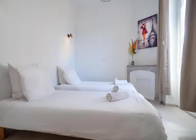 two white beds in a room with a fireplace at Grand appartement 4 pièces centre de Cannes in Cannes
