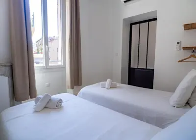 two white beds in a room with a window at Grand appartement 4 pièces centre de Cannes in Cannes