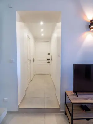 a hallway with a white door and a tv at Grand appartement 4 pièces centre de Cannes in Cannes
