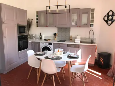 a kitchen with a table and white chairs in it at Appartement Suquet Forville in Cannes