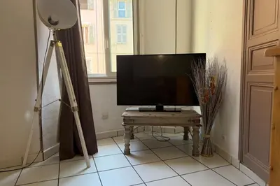 a television on a stand in a room with a table at 1-bedroom apt 5 minutes from the Congress Center in Cannes