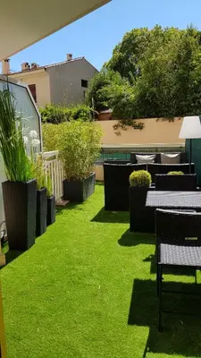 a green yard with tables and chairs and plants at Studio Center Cannes grande Terasse in Cannes