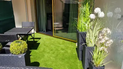 a patio with grass and chairs and a mirror at Studio Center Cannes grande Terasse in Cannes