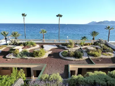 a garden with palm trees and the ocean in the background at Résidence Saint Rémy 2 in Cannes