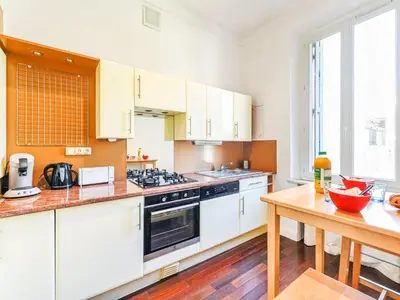 a kitchen with white cabinets and a wooden table at Apartment Villa Chalmette by Interhome in Cannes