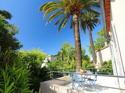 a table and chairs on a balcony with a palm tree at Holiday Home Villa Esmeralda by Interhome in Cannes
