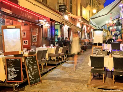 a woman walking through a restaurant with tables and chairs at Holiday Home Villa Esmeralda by Interhome in Cannes