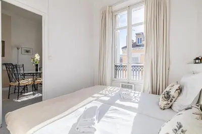 a white bedroom with a large bed and a window at L'ESCAPADE CITADINE avec 2 chambres, proche de la Croisette, des plages et du Palais in Cannes