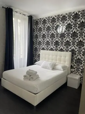 a bedroom with a white bed with a black and white wallpaper at Studios des Congrès et Festivals in Cannes
