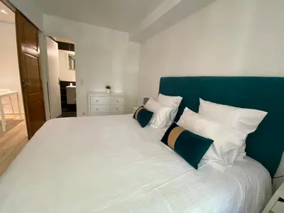 a bed with white pillows and a green headboard at 2 pièces - Croisette et Plages à 10 mn à pieds in Cannes