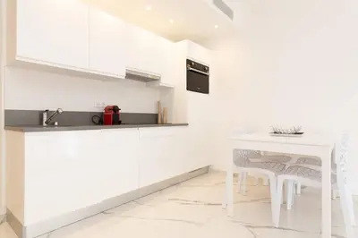 a kitchen with white cabinets and a white table and chairs at Brand new 2 bedrooms next to Croisette ! in Cannes