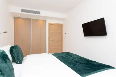a bedroom with a white bed and a flat screen tv at Brand new 2 bedrooms next to Croisette ! in Cannes
