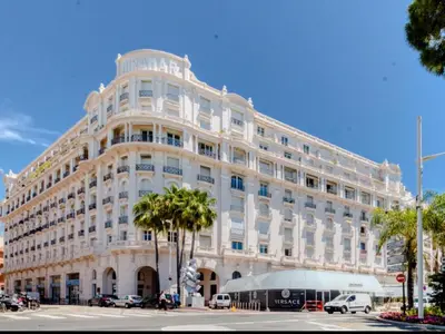 a large white building with palm trees in front of it at Cannes Croisette Majestic Miramar in Cannes
