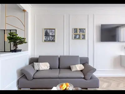 a living room with a couch and a tv at Cannes Croisette Majestic Miramar in Cannes