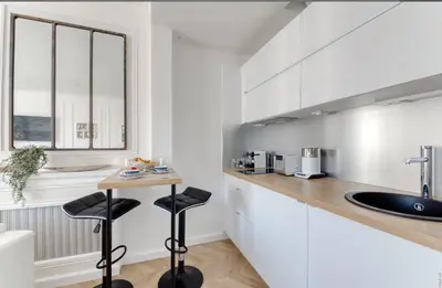 a kitchen with white cabinets and a counter with stools at Cannes Croisette Majestic Miramar in Cannes