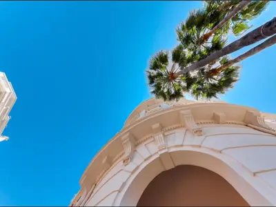 a building with a palm tree in the sky at Cannes Croisette Majestic Miramar in Cannes