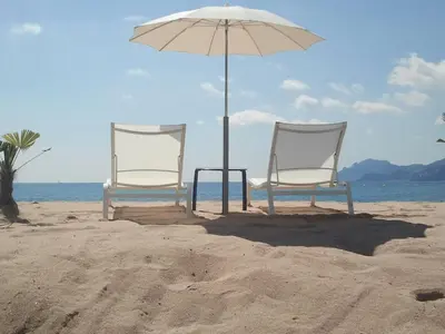 two chairs and an umbrella on the beach at Appartement Cannes à quelques pas de la mer, de la Croisette et du Palais des Festivals in Cannes
