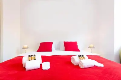 a large white bed with red pillows on it at Astoux YourHostHelper in Cannes