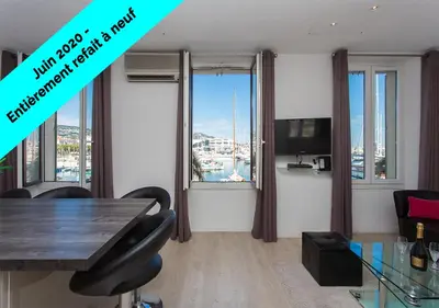 a living room with a table and chairs and windows at COTE PORT in Cannes