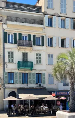 a building with tables and umbrellas in front of it at COTE PORT in Cannes