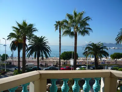 a balcony with palm trees in a parking lot at Appartement Relais de la Reine Cannes Croisette in Cannes