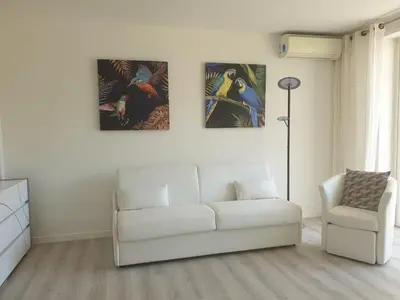 a living room with a white couch and three paintings on the wall at STUDIO LES ALGUES in Cannes