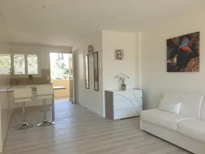 a white living room with a couch and a kitchen at STUDIO LES ALGUES in Cannes