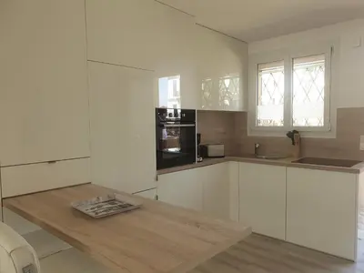 a kitchen with white cabinets and a wooden table at STUDIO LES ALGUES in Cannes