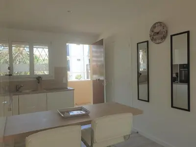 a kitchen with a table and a clock on the wall at STUDIO LES ALGUES in Cannes