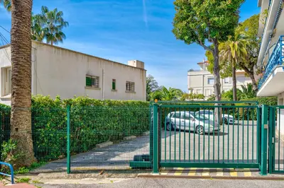 a green gate with a car parked in a parking lot at Cannes Les Pins in Cannes
