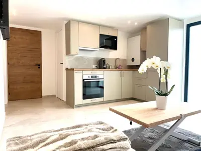 a kitchen with white cabinets and a table with flowers at Appartment Jacuzzi in Cannes in Cannes